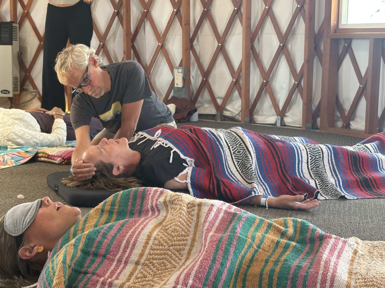 Scot offering supportive touch to a participant resting during a breathwork session