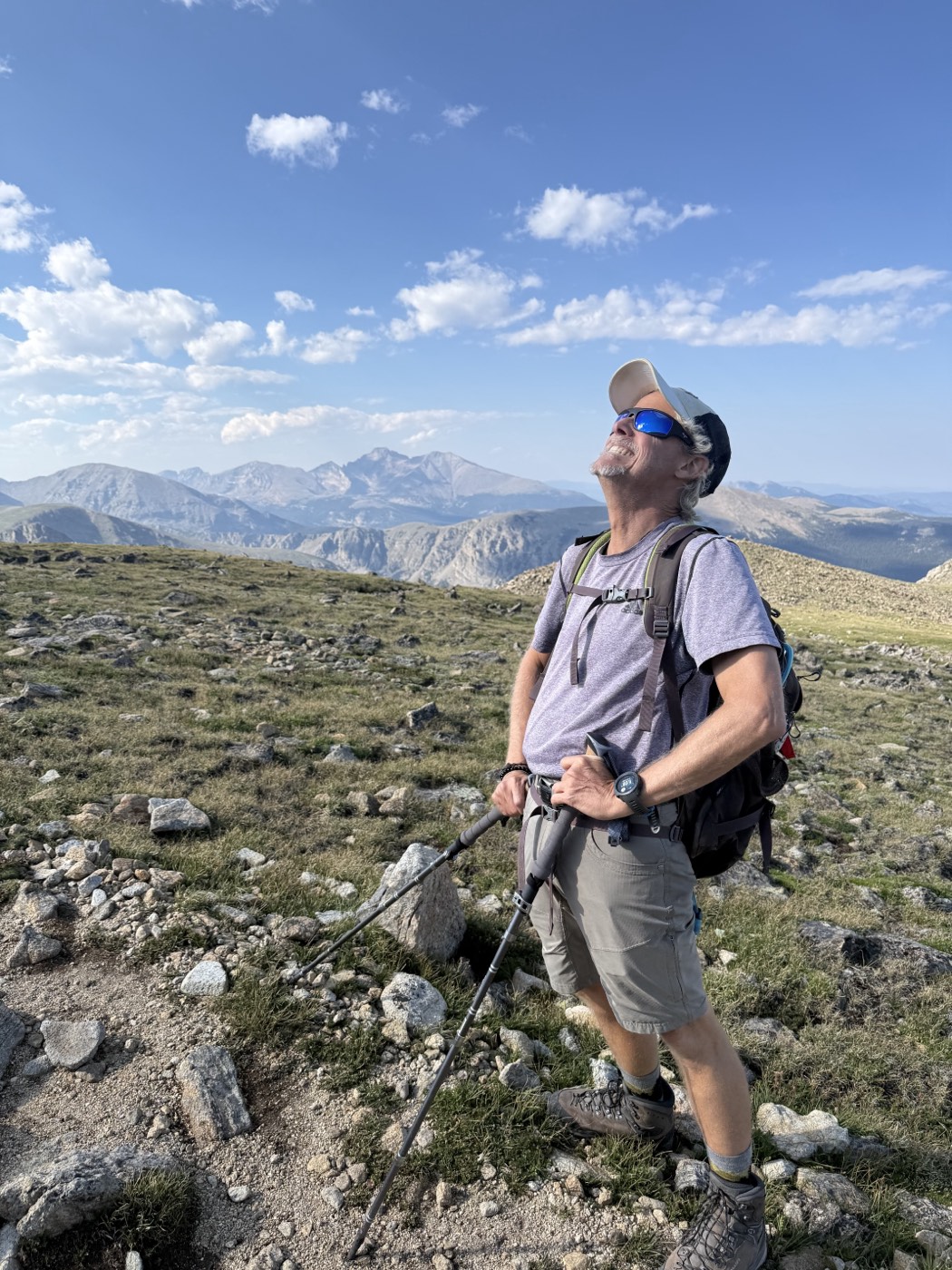 Scot standing on a Colorado mountain summit, looking up at the sky